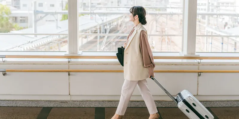スーツケースを引いて駅の通路を歩く人