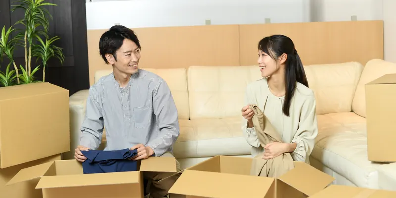新しい住まいで段ボールを開けて荷ほどきをする二人